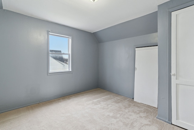 additional living space featuring light colored carpet and vaulted ceiling