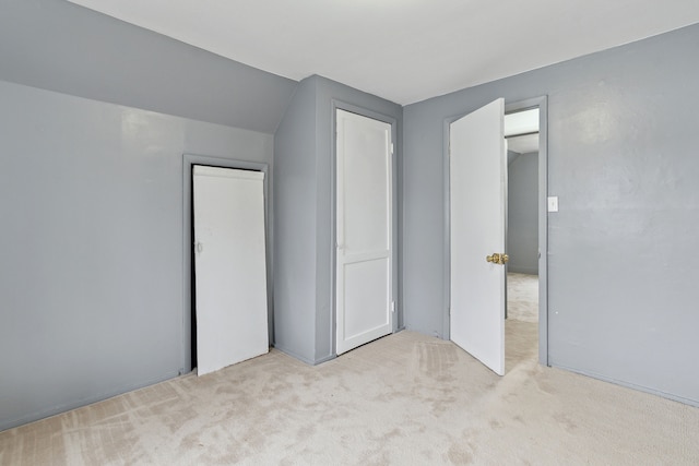 unfurnished bedroom featuring light colored carpet, a closet, and lofted ceiling