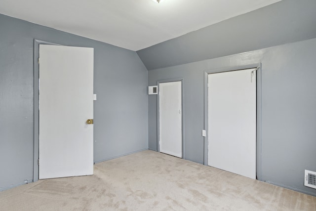 unfurnished bedroom with light colored carpet and lofted ceiling