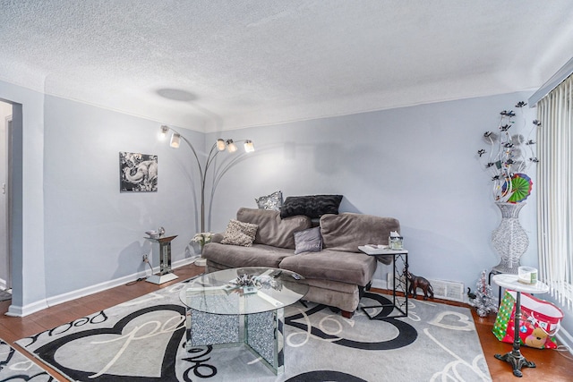 living area featuring visible vents, baseboards, a textured ceiling, and wood finished floors