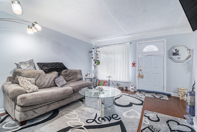 living area featuring a textured ceiling, baseboards, and wood finished floors