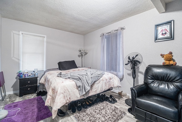 bedroom with baseboards, a textured ceiling, and wood finished floors