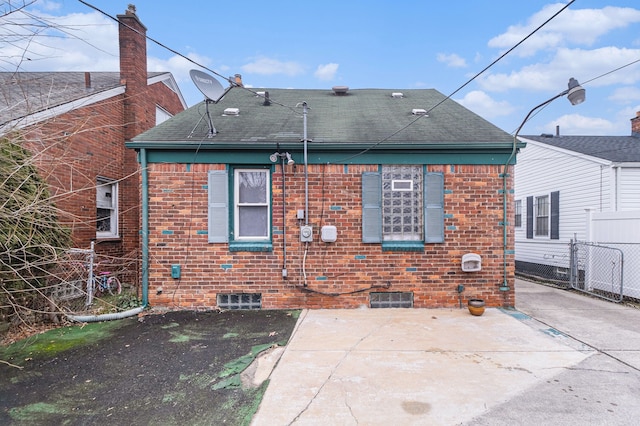 rear view of house with a patio area, brick siding, roof with shingles, and fence