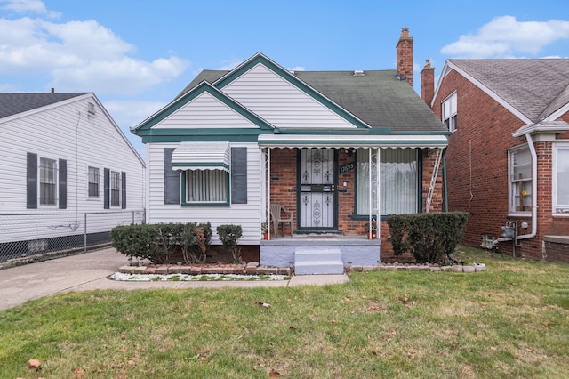 bungalow-style house featuring brick siding, a chimney, and a front lawn