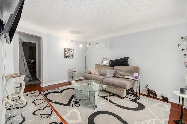 living area featuring baseboards, a textured ceiling, and wood finished floors