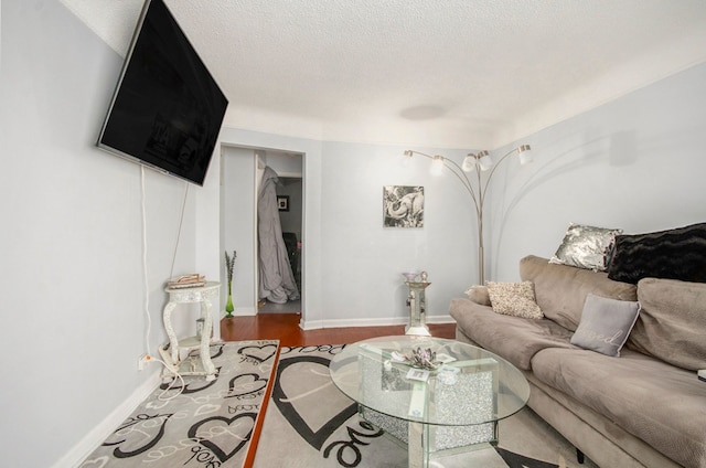 living area with a textured ceiling, baseboards, and wood finished floors