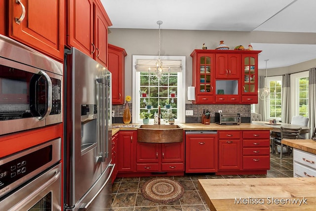 kitchen featuring sink, hanging light fixtures, decorative backsplash, stainless steel appliances, and a chandelier