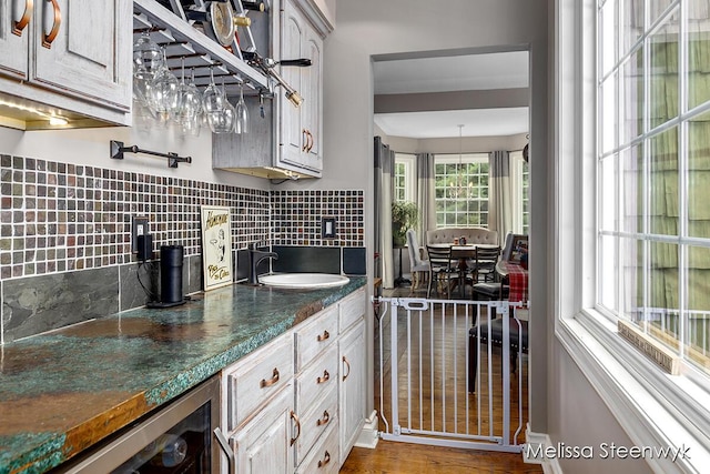 kitchen featuring backsplash, sink, dark stone countertops, white cabinets, and wine cooler