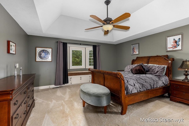 carpeted bedroom with ceiling fan and a tray ceiling