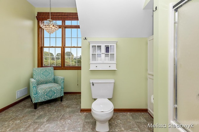 bathroom with toilet and an inviting chandelier