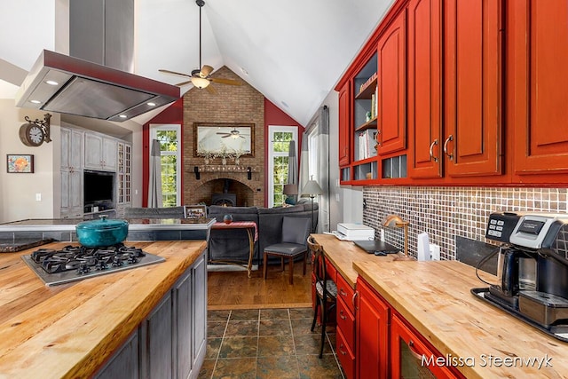 kitchen with ceiling fan, wood counters, tasteful backsplash, vaulted ceiling, and island range hood