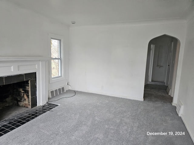 unfurnished living room with dark carpet and a tile fireplace