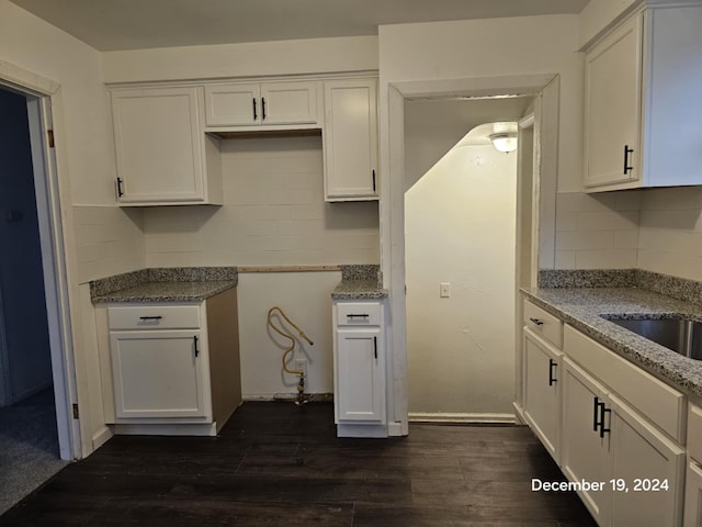 kitchen with dark wood-type flooring, sink, decorative backsplash, light stone countertops, and white cabinetry