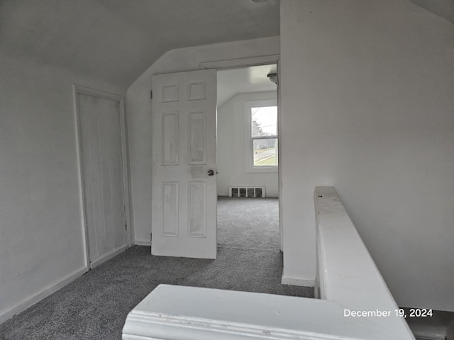 additional living space with dark carpet and lofted ceiling