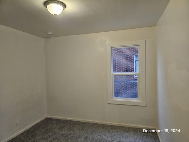 unfurnished room with dark colored carpet