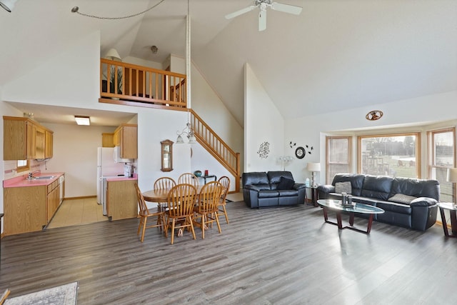 living room with ceiling fan, light wood-type flooring, sink, and high vaulted ceiling