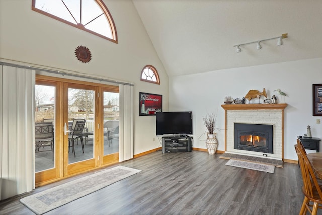 unfurnished living room with a fireplace, hardwood / wood-style floors, rail lighting, and high vaulted ceiling