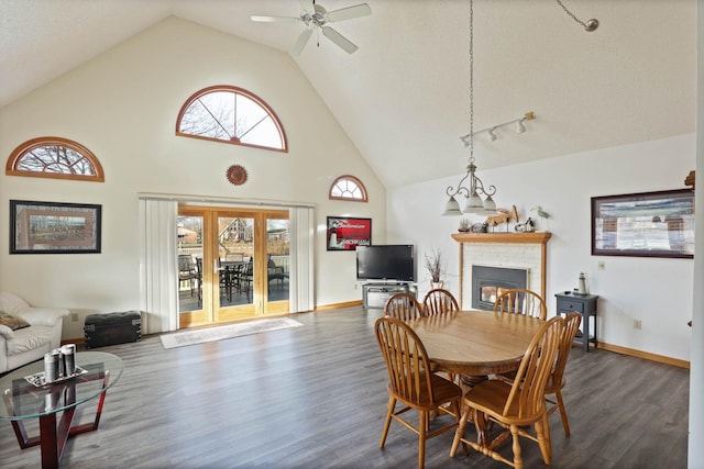 dining area featuring a fireplace, dark hardwood / wood-style flooring, high vaulted ceiling, and ceiling fan