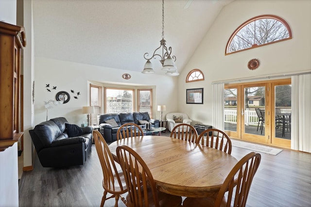 dining area featuring high vaulted ceiling, a healthy amount of sunlight, dark hardwood / wood-style floors, and a notable chandelier