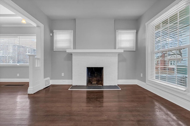 unfurnished living room featuring dark hardwood / wood-style floors and a brick fireplace