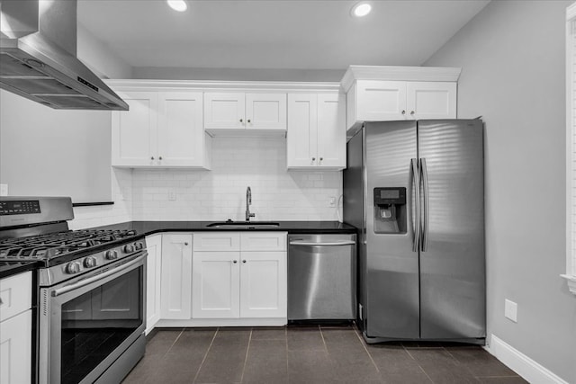 kitchen with white cabinets, wall chimney range hood, sink, appliances with stainless steel finishes, and tasteful backsplash