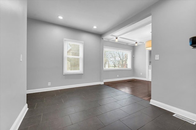 tiled spare room with beamed ceiling