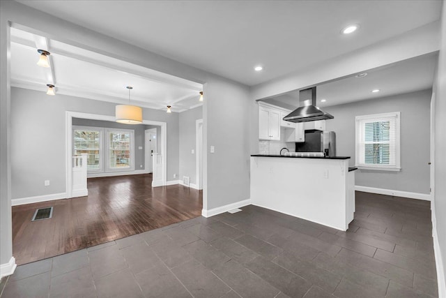 kitchen with kitchen peninsula, hanging light fixtures, dark tile patterned floors, white cabinetry, and stainless steel fridge with ice dispenser