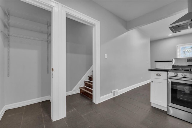 kitchen featuring white cabinets, range hood, and stainless steel range