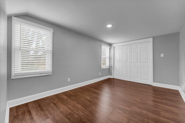 unfurnished bedroom featuring a closet, dark wood-type flooring, and vaulted ceiling