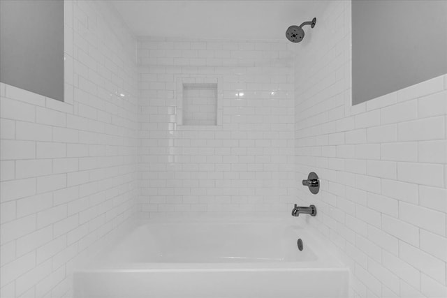 bathroom with tiled shower / bath combo and tile walls