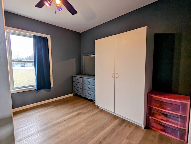 unfurnished bedroom featuring ceiling fan, a closet, light hardwood / wood-style flooring, and multiple windows