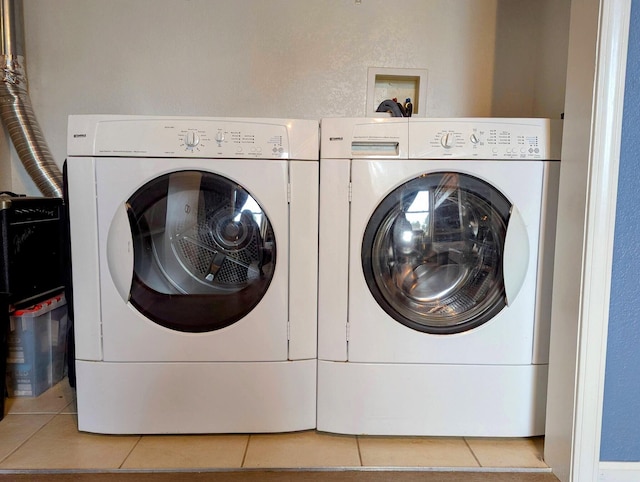 laundry room featuring washing machine and clothes dryer and light tile patterned floors