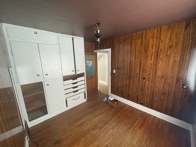 unfurnished bedroom featuring wooden walls, a closet, and dark hardwood / wood-style floors