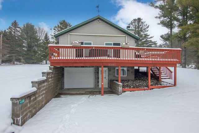 snow covered house with a garage and a deck