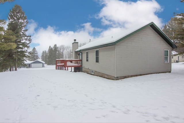 snow covered property with an outdoor structure and a garage