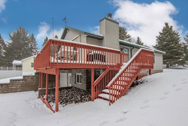 snow covered house featuring a wooden deck