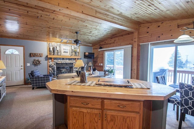 kitchen with carpet flooring, wood counters, a kitchen island with sink, wooden ceiling, and wood walls