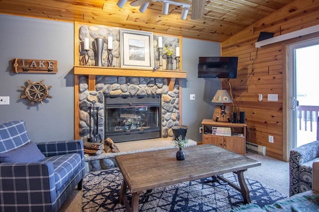 living room with carpet flooring, a baseboard radiator, wooden ceiling, a stone fireplace, and wooden walls