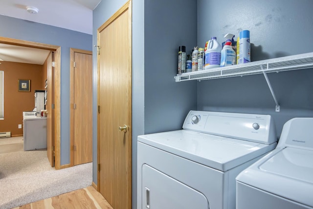 clothes washing area featuring washer and dryer, light wood-type flooring, and a baseboard heating unit