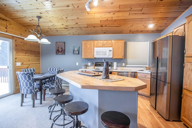 kitchen with stainless steel appliances, butcher block countertops, pendant lighting, a kitchen island, and wood ceiling