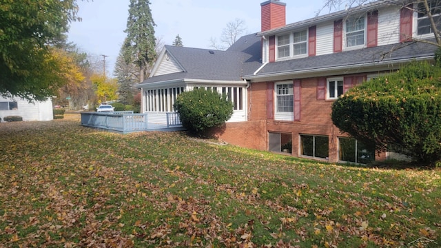 rear view of house with a sunroom and a lawn