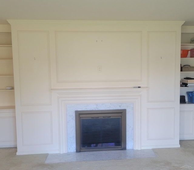 room details with a fireplace, built in features, crown molding, and carpet floors