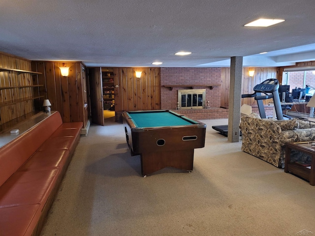 playroom featuring a brick fireplace, a textured ceiling, wooden walls, carpet, and pool table