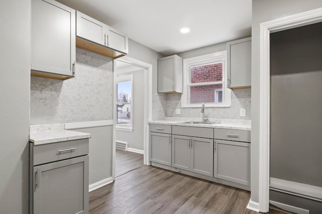 kitchen featuring tasteful backsplash, gray cabinetry, sink, and wood-type flooring