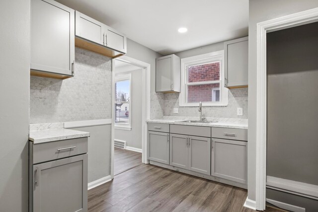 kitchen featuring gray cabinets, hardwood / wood-style flooring, sink, and backsplash