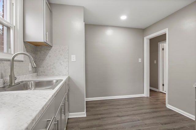 kitchen with backsplash, gray cabinetry, sink, and dark wood-type flooring