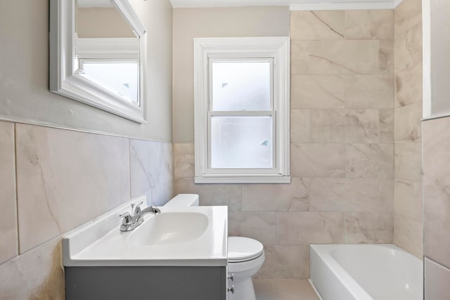 bathroom featuring a washtub, tile patterned flooring, toilet, vanity, and tile walls