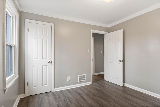 unfurnished bedroom with dark hardwood / wood-style floors, ornamental molding, and multiple windows