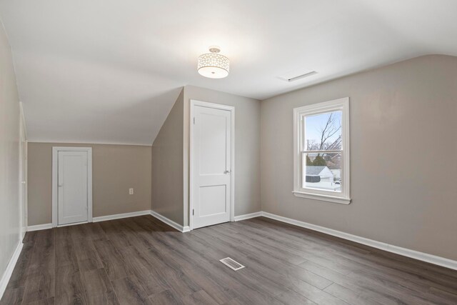 additional living space featuring dark wood-type flooring and lofted ceiling