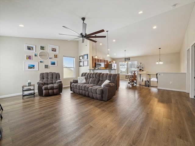 living room with ceiling fan with notable chandelier, vaulted ceiling, and dark hardwood / wood-style floors